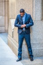 Young black man standing outdoors in New York City, looking down, checking his sleeves Royalty Free Stock Photo