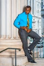 Young black businessman standing outside office, texting on cell phone Royalty Free Stock Photo