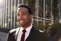 Young black businessman wearing black suit standing on the street smiling, close up with lens flare Royalty Free Stock Photo