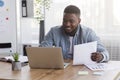 Young black businessman working with laptop and papers in office Royalty Free Stock Photo