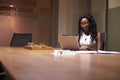 Young black businesswoman working late on laptop in office