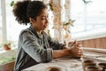 Young black ceramist woman sculpting in clay at her workshop