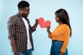 Young black couple connecting two halves pieces of broken hearts