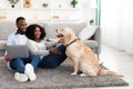 Young black couple at home using laptop playing with pet Royalty Free Stock Photo
