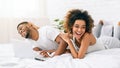 Young black couple lying on bed and using laptop. Royalty Free Stock Photo