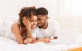 Young black couple lying on bed and using laptop. Royalty Free Stock Photo