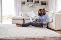 Young black couple sit on the floor using laptop, side view Royalty Free Stock Photo