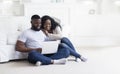 Young black couple using laptop at home planning summer vacation