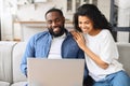 Young black couple using laptop sitting on the sofa at home