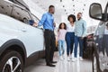 Young black family having conversation with confident sales agent about buying new car at auto dealership Royalty Free Stock Photo