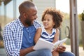 Young black father and daughter reading book outside