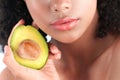 Young black girl with clean perfect skin with avocado close-up