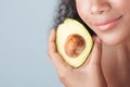 Young black girl with clean perfect skin with avocado close-up