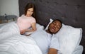 Young black guy snoring and bothering his angry sleepless wife in bed at home Royalty Free Stock Photo