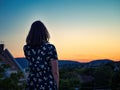 Young black hair girl in a floral dress looking at a colorful city sunset Royalty Free Stock Photo