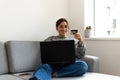 young black-haired woman shopping online from the sofa at home with the computer and credit or debit Royalty Free Stock Photo