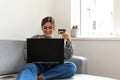 young black-haired woman shopping online from the sofa at home with the computer and credit or debit Royalty Free Stock Photo