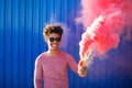 Young black hipster man smiling and holding a colorful pink smoke Royalty Free Stock Photo
