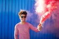 Young black hipster man smiling and holding a colorful pink smoke Royalty Free Stock Photo