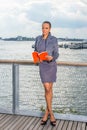 A young black lady is reading a red book on the dock by a river Royalty Free Stock Photo