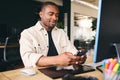 Young Black Male Advertising Marketing Or Design Creative In Modern Office Sitting At Desk Using Mobile Phone Royalty Free Stock Photo