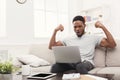 Young black man with arms raised with laptop celebrating success Royalty Free Stock Photo