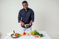 Young black man cooking at home domestic kitchen and preparing a vegetarian meal.vegan food on white background in Royalty Free Stock Photo