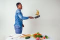 Young black man cooking at home domestic kitchen and preparing a vegetarian meal.vegan food on white background in Royalty Free Stock Photo