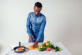 Young black man cooking at home domestic kitchen and preparing a vegetarian meal.vegan food on white background in Royalty Free Stock Photo