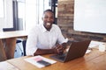 Young black man at desk with laptop computer looks to camera Royalty Free Stock Photo