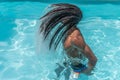 Young black man with dreadlocks inside a pool moving his wet hair in a trail of water Royalty Free Stock Photo