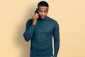 Young black man having conversation talking on the smartphone looking positive and happy standing and smiling with a confident Royalty Free Stock Photo