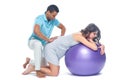 A young black man helps his white wife with birth pain with a ball. Partnered birth, partnered delivery. Isolated white