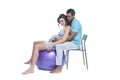 A young black man helps his white wife with birth pain with a ball. Partnered birth, partnered delivery. Isolated white