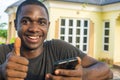 young black man holding his mobile phone smiling and giving a thumbs up Royalty Free Stock Photo