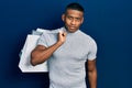 Young black man holding shopping bags looking positive and happy standing and smiling with a confident smile showing teeth Royalty Free Stock Photo