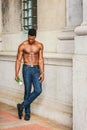 Young black man holding white rose, standing outdoors in New York City, looking down, thinking Royalty Free Stock Photo