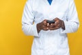 A young black man in a lab coat using his phone