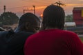 young black man and lady sitting together outside having a conversation while the sun sets