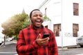 Young black man laughing with cellphone outside in city Royalty Free Stock Photo