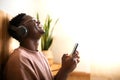 Young black man Listening to music with wireless headphones using mobile phone at home. Blissful moments. Copy space. Royalty Free Stock Photo