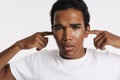 Young black man looking at camera while plugging his ears Royalty Free Stock Photo