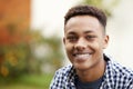 Young African American man outdoors smiling to camera, close up, head and shoulders