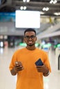 Young black man ready to travel at airport terminal waiting for flight while using phone Royalty Free Stock Photo