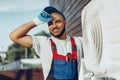 Young black man repairman checking an outside air conditioner unit