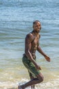 Young black man, shirtless, walking on beach, smiling, looking around Royalty Free Stock Photo