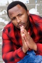 Young black man sitting down and praying with hands clasp Royalty Free Stock Photo
