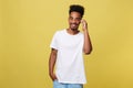 Young black man smiling and talking on mobile phone with copy space over yellow background. Royalty Free Stock Photo