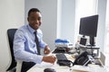 Young black man smiling to camera from his desk in an office Royalty Free Stock Photo