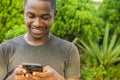 young black man smiling while viewing content on his mobile phone, texting and browsing the internet Royalty Free Stock Photo